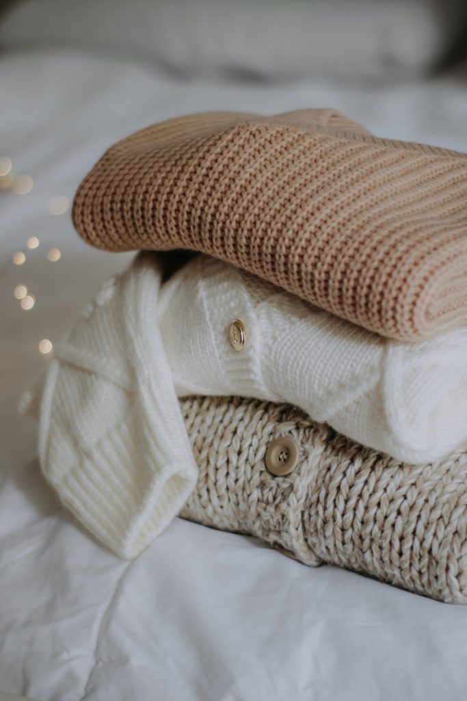 sweaters folded on the bed