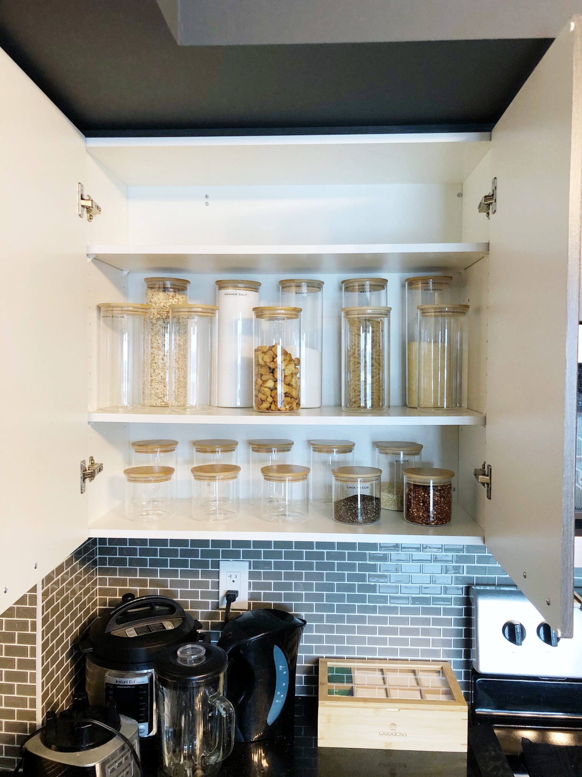 Space-saving kitchen organization in a Beltline Calgary apartment using glass canisters with bamboo lids
