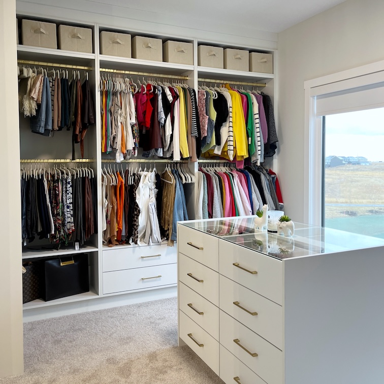 Sophisticated primary suite closet organization in Bel-Aire, Calgary, showcasing a custom island and simplified inventory management.