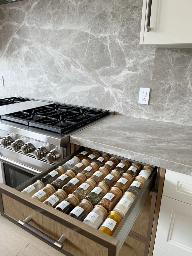 Spice drawer organization in Elbow Park featuring uniform glass jars and sustainable bamboo lids for a sophisticated kitchen.